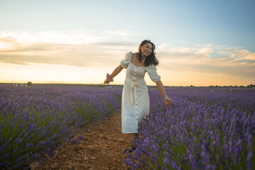outdoors romantic portrait of young happy and attractive woman in white summer dress enjoying carefree at beautiful lavender flowers field in travel and holiday concept