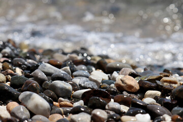 Pebble stones on blurred background of sea waves. Summer vacation concept