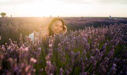 outdoors romantic portrait of young happy and attractive woman in white summer dress enjoying carefree at beautiful lavender flowers field in travel and holiday concept