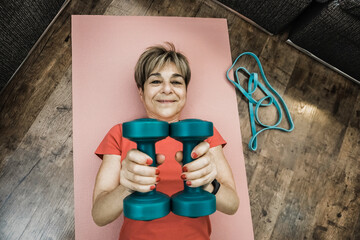 Senior woman doing workout routine t home - Elderly sport and healthy lifestyle - Focus on face