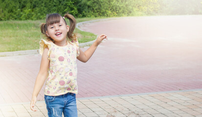 Naklejka premium Little happy jumping girl. Happy child on the street. Outdoor games