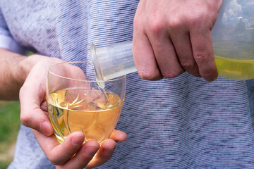 the winemaker pours white wine from a bottle into a glass
