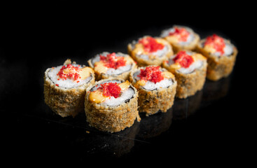 baked japanese rolls with red caviar on a black background