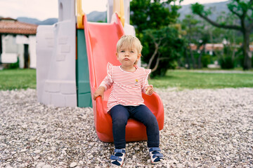 Fototapeta na wymiar Little girl sitting on a slide in the playground