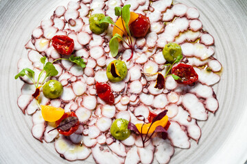 Octopus carpaccio. Spinach cream, cherry tomatoes. Delicious healthy Italian traditional food closeup served for lunch in modern gourmet cuisine restaurant