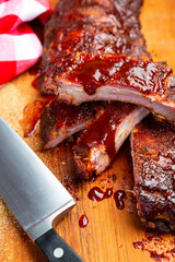 Closeup of pork ribs grilled with caramelized BBQ sauce. Tasty snack on a wooden Board