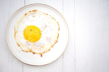 fried egg on a white plate on a wooden white table