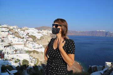 Fototapeta na wymiar Happy beautiful woman traveller wearing face mask travelling in Santorini Greece during summer holidays. 