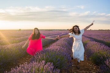 young happy and beautiful Asian korean woman playing on lavender flowers field with her hispanic girlfriend enjoying sweet holidays together relaxed and carefree