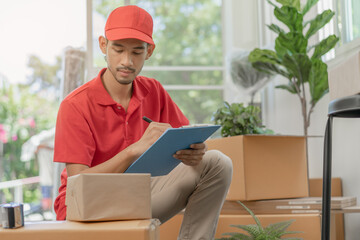 Service, delivery asian man, male checking list stuff, parcel or cardboard box, carton in warehouse before deliver to customer address. Courier working in uniform. Moving in new relocation.