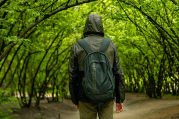 man walking and relaxing in park. Tourist with backpack walking in park. Spending time alone in nature. Peaceful atmosphere. Back view.