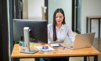 Young Business woman working on laptop computer for do math finance on wooden desk, tax, accounting, statistics report and analytical research concept