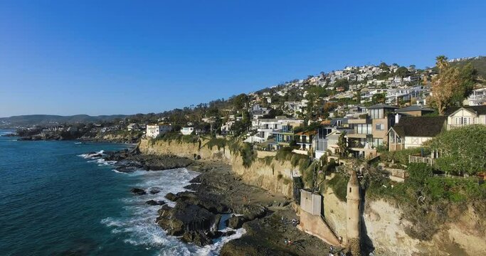 Drone flies along the ocean coast with numerous houses, aerial footage from Laguna Beach, California, USA