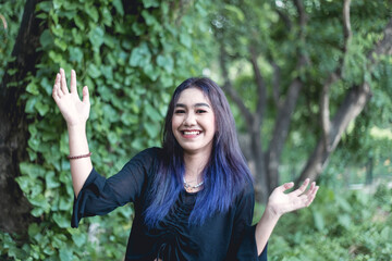 Portrait of a bubbly, animated and cheerful asian goth girl with purple dyed hair posing outdoors.