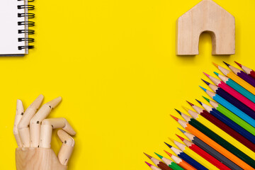Wooden hand and many crayon placed on a yellow color background. Education and back to school concept.