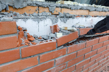 the builder breaks the brickwork of the wall with a tool