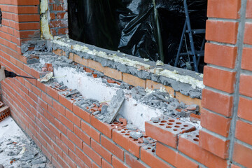 the builder breaks the brickwork of the wall with a tool