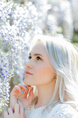 Portrait of a young beautiful woman in a blooming garden. Spring. Wisteria.