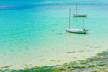 Two white fishing boats in bay near Le Hocq Tower on the south shore of Jersey, Channel Islands, Britain, on a sunny summer day.