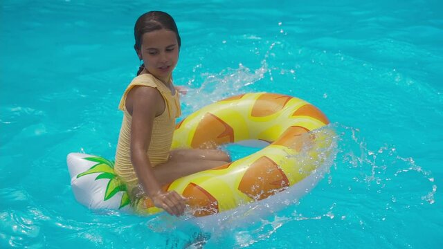 Kid swim on inflatable pineapple ring in pool of the water park. Cheerful girl teenager plays in pool and an inflatable circle. Holidays, Vacations, Recreations, Sport, Children, Water, Hotel