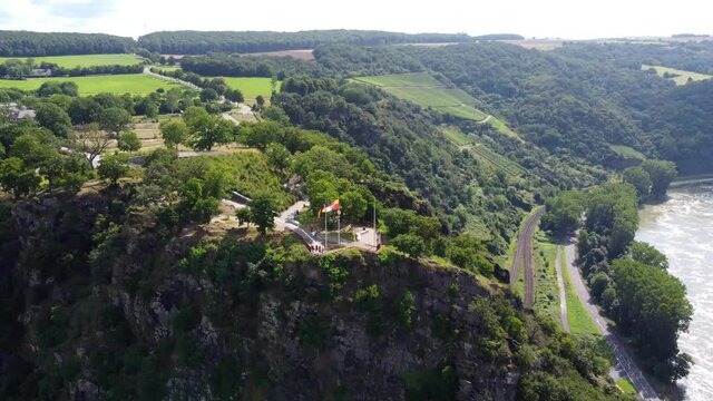 Video from a drone moving away from a cliff on the Rhine in Germany, visible road on both sides of the river.