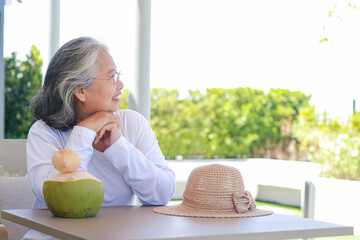 Happy Asian elderly woman wearing white shirt Sit and enjoy the cool natural breeze. The concept of...