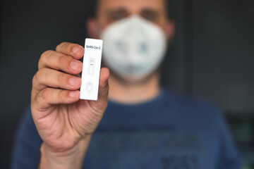 Mann mit FSP2 Maske zeigt negativen Coronateststreifen vor