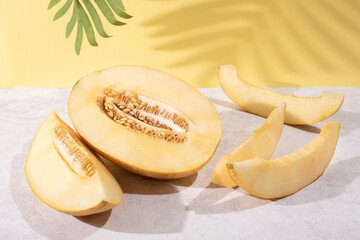 Juicy melon half and slices on a yellow background with beautiful shadows.