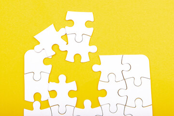 white jigsaw puzzle pieces isolated on a yellow background