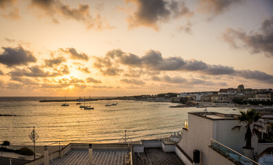 Fototapeta premium Beautiful sunrise in Otranto town bay, Apulia, Adriatic Sea, Salento, Italy. No people. Soft golden colors, cloudy sky. Summer morning in Italy.