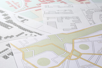 Many different cadastral maps of territory with buildings as background, closeup