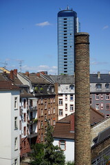 Hoher alter Fabrikschornstein und moderne Glasfassade eines Hochhaus vor blauem Himmel bei...