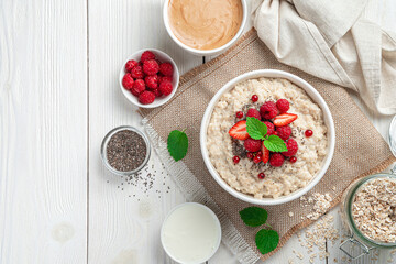 Breakfast with oatmeal with healthy berries and chia seeds on a light background. Vegetarian food. Top view, copy space.