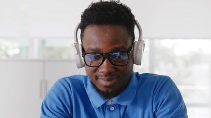 Close up of african businessman with headphones and computer working at office