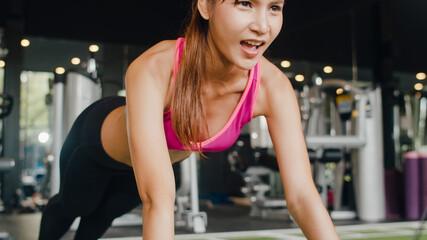 Fototapeta na wymiar Beautiful young athlete Asian lady exercise doing push-ups fat burning workout in fitness class. Sportswoman recreational activity, functional training, people working out, healthy lifestyle concept.