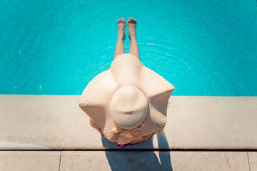 Unrecognizable young woman in big hat relaxing in the pool at the spa resort. Relaxing concept