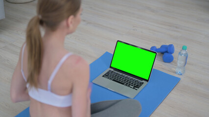 Rear View of Woman doing Yoga while Looking at Laptop with Chroma Key Screen 
