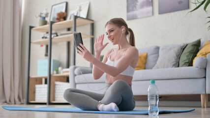 Woman Talking on Video Call on Smartphone while Sitting on Yoga Mat 
