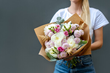 Woman holds a bouquet of peonies.