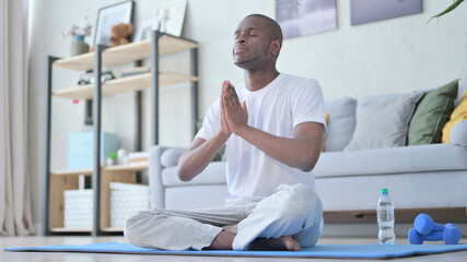 Obraz premium African Man Meditating on Yoga Mat at Home
