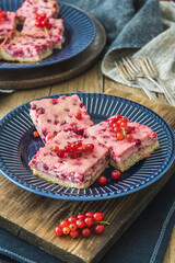 Pieces of creamy red currant pie on a blue plate on wooden background, vertical
