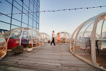 a man and a woman in love walk to a rooftop cafe on a date.