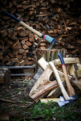Firewood and logs in one pile, with Two axes with steel blades. Chopping wood as a solid fuel. Concept: harvesting firewood for the winter.