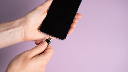 Phone in a hand. Charging smartphone. Plugin Type-C cord into the phone. Charging battery on a mobile phone