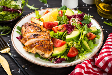 Healthy food concept. Grilled chicken with fresh salad at dark wooden table.