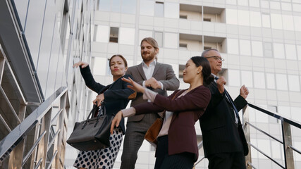 Happy excited business people celebrating success together dancing outside office building