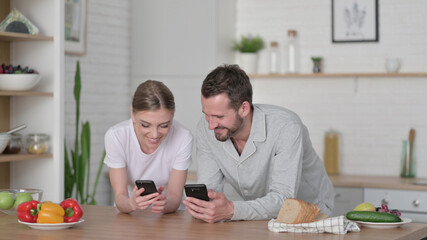 Happy Couple using Smartphone in Kitchen 