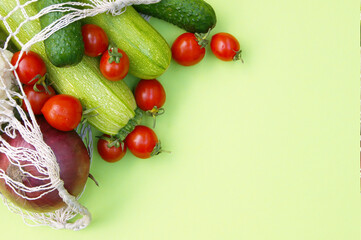 Ripe juicy red tomatoes, green cucumbers and zucchini in a string bag.