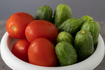 Freshly harvested tomatoes and cucumbers in a new white flower pot. Home farm agriculture concept