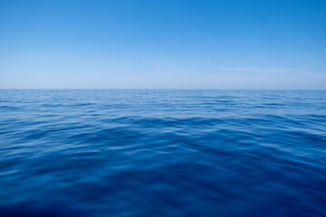 Sea water surface calm with small ripples, deep blue color and blue sky background,